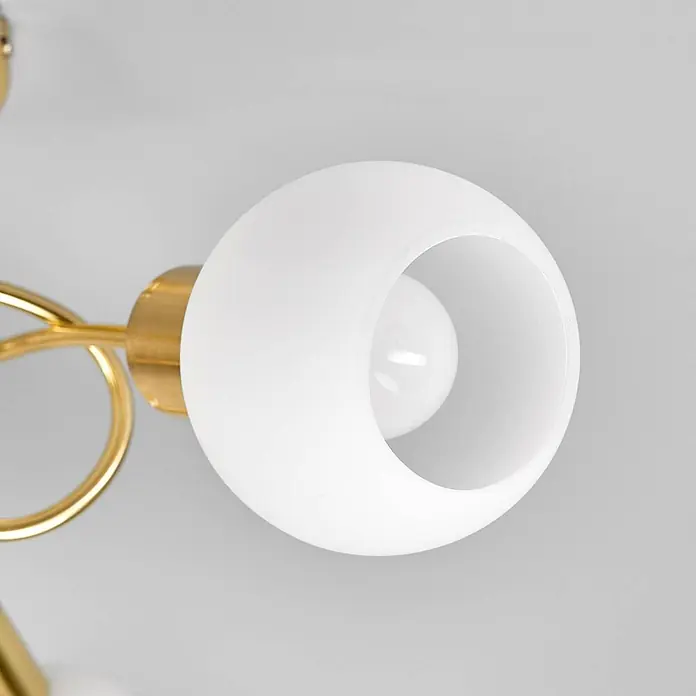 Lindby Deckenleuchte Elaina - messing / gold, E14 - Eine moderne Leuchte mit goldenem Sockel und weißem, kugelförmigem Schirm mit kreisrunder Öffnung, die eine Glühbirne enthüllt.
