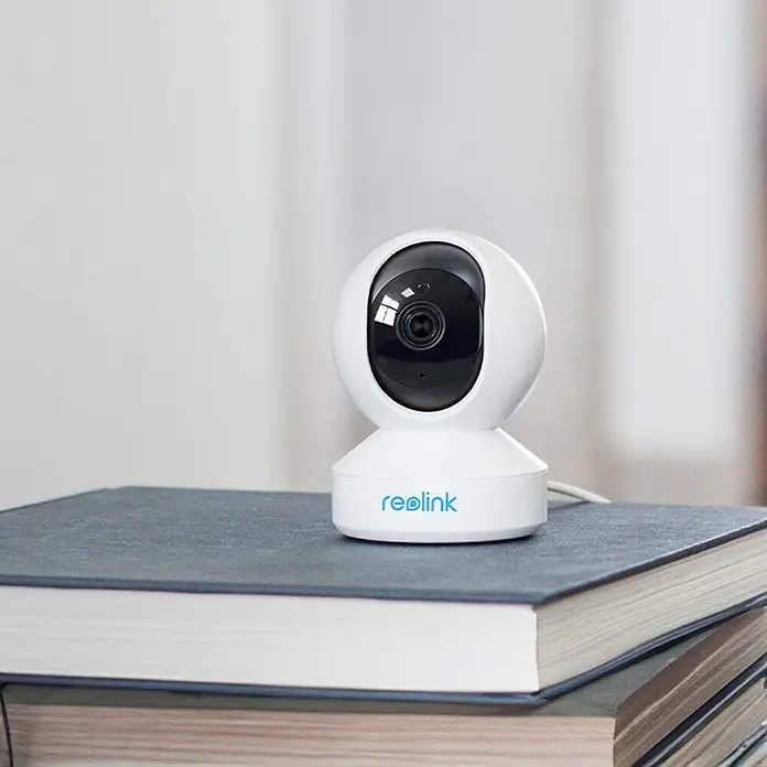 Reolink Überwachungskamera E330 5 MP WLAN -  - Weiße Reolink Überwachungskamera mit schwarzer Linse, auf einem Stapel Bücher.