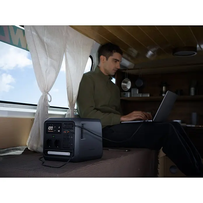 DJI Powerstation Power 1000 Mini - 1.008 Wh, Schwarz - Dunkelgraue, tragbare Powerstation mit Digitalanzeige, die einen Laptop in einem Wohnmobil mit Strom versorgt. Zeigt 100% Akku und 98W Leistung.