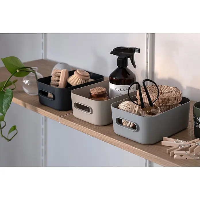 SmartStore Aufbewahrungsbox Comfort S - L x B x H: 20 x 14 x 7,5 cm, Kunststoff, Dark Teal, 1,5 l - Drei rechteckige Aufbewahrungsboxen in Dunkelgrau, Beige und Hellgrau, ordentlich auf einem Holzregal mit Reinigungs- und Haushaltsartikeln.