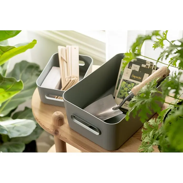 SmartStore Aufbewahrungsbox Comfort M - L x B x H: 29,5 x 19,5 x 12 cm, Kunststoff, Aquaverde, 5,3 l - Zwei graue Aufbewahrungsboxen mit Gartenwerkzeugen und Pflanzenmarkern auf einem Holztisch.