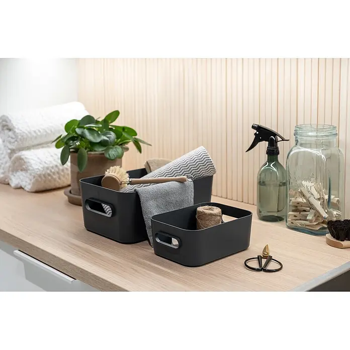 SmartStore Aufbewahrungsbox Comfort S - L x B x H: 20 x 14 x 7,5 cm, Kunststoff, Dark Teal, 1,5 l - Dunkelgraue Aufbewahrungsboxen in zwei Größen auf einer Holztheke, zur Organisation von Haushaltsartikeln und Textilien.