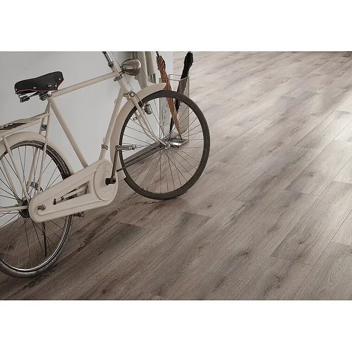 Krono Original Laminat Atlantic 7 - Dove Cantal Oak, Landhausdiele, 1.288 x 245 x 7 mm - Heller, holzimitierender Laminatboden in einem Raum mit Fahrrad und Schirmständer.