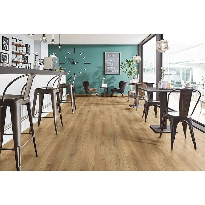 Krono Original Laminat Atlantic 7 - Sand Cantal Oak, Landhausdiele, 1.288 x 195 x 7 mm - Natürlicher Laminatboden in Holzoptik in einem Café mit Barhockern und Tischen, der Haltbarkeit und eine einladende Ästhetik unterstreicht.