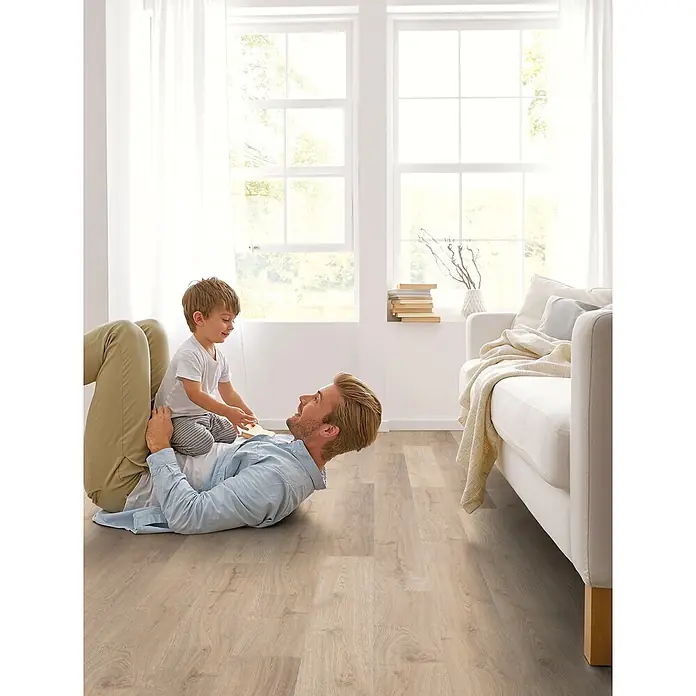 Decolife Designboden Freestyle Access Hardy Oak - 1.220 x 185 x 8,5 mm, Landhausdiele, Hardy Oak - Heller Boden in Holzoptik mit natürlicher Eichenholzmaserung, gezeigt in einem Wohnzimmer, in dem Vater und Kind spielen.