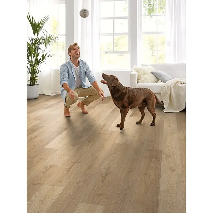 Decolife Designboden Freestyle Access Hazel Oak - 1.220 x 185 x 8,5 mm, Landhausdiele, Hazel Oak - Helles Holzboden in einem modernen Wohnzimmer mit spielendem Mann und Hund.