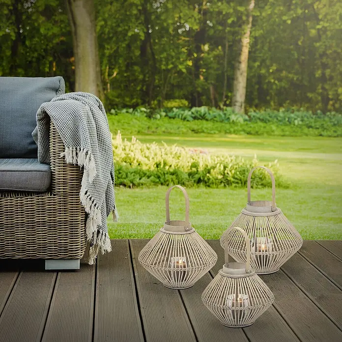 ECD Germany Windlicht Boho Bambus Laterne - Ø x H: 35 x 44 cm, Natur, 1 Stk. - Drei natürliche Rattan-Laternen mit brennenden Kerzen stehen auf einer dunklen Holzterrasse und schaffen Außenambiente.