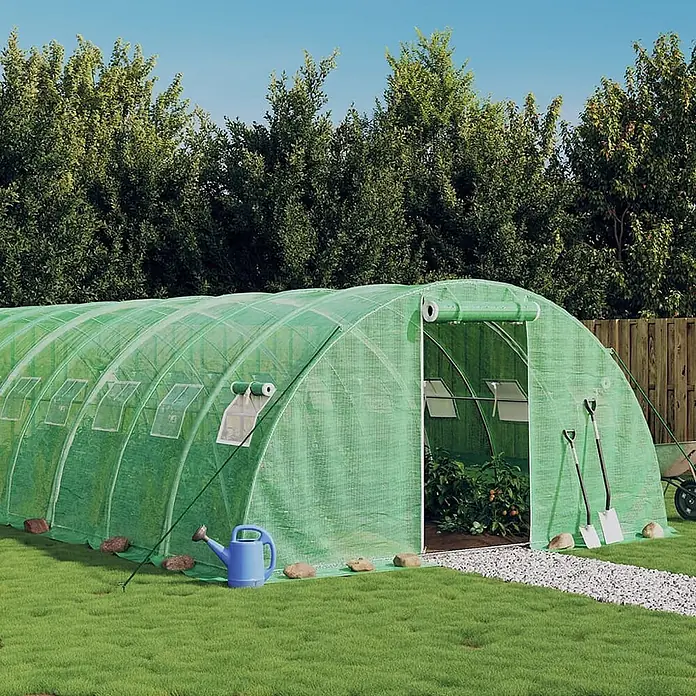 Furnicato Gewächshaus - Außenmaß inkl. Dachüberstand (B x T): 400 x 1.600 cm, Material Seitenwand: Kunststoff, 38 mm, Grau - Großer grüner Folientunnel im Garten, offener Eingang mit Pflanzen und Gartengeräten davor.