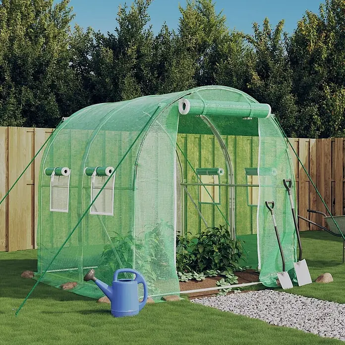 Furnicato Gewächshaus - 2 x 2 cm, Material Seitenwand: Kunststoff, 38 mm, Grau - Ein großes grünes Maschen-Tunnelgewächshaus im Garten mit Pflanzen. Eine blaue Gießkanne und Schaufeln sind in der Nähe.