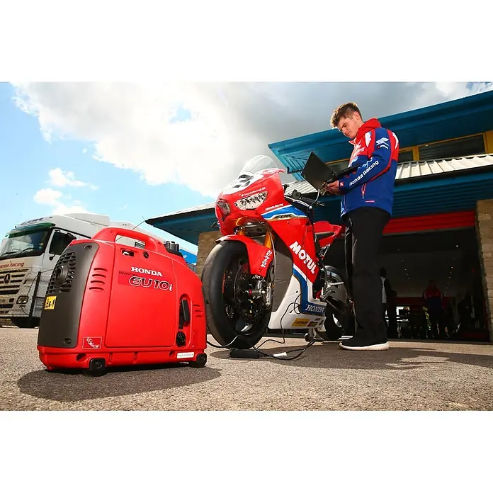 Honda Stromerzeuger EU 10i - Nennleistung: 1,1 kW, Tankvolumen: 2,1 l - Roter Honda EU10i Inverter-Generator lädt ein Rennmotorrad.