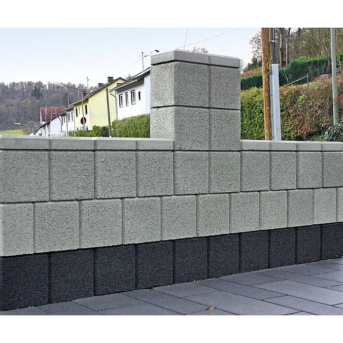 Christoph Mauerabdeckplatte Ambienta - 40 x 20 x 5 cm, Grau, Beton - Strukturierte Betonsteine bilden eine hellgraue Mauer und einen Pfeiler mit dunkelgrauem Sockel in einem Wohnbereich.