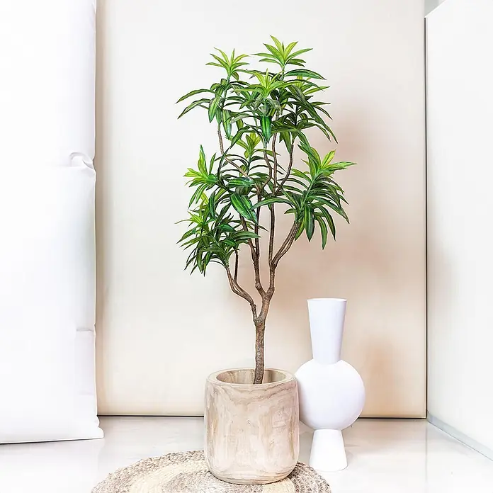 Florora Kunstpflanze Drachenbaum - Höhe: 130 cm, Holz - Hohe Kunstpflanze mit grünen Blättern in Holztopf, neben moderner weißer Vase, auf geflochtener Matte.