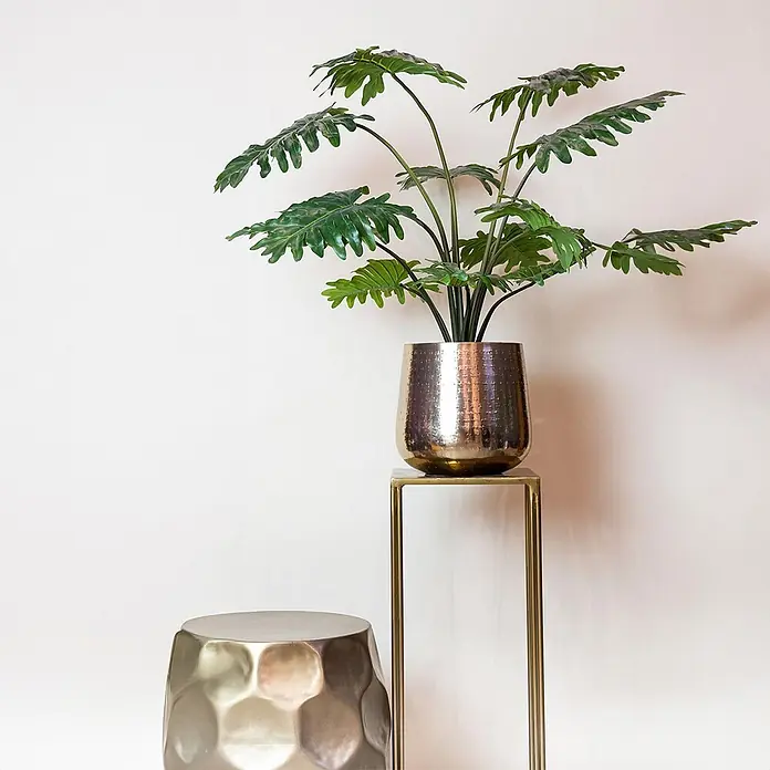 Florora Kunstpflanze Philodendron - Holz - Metallischer gehämmerter Pflanzkübel auf einem Ständer neben einem passenden sechseckigen Beistelltisch.