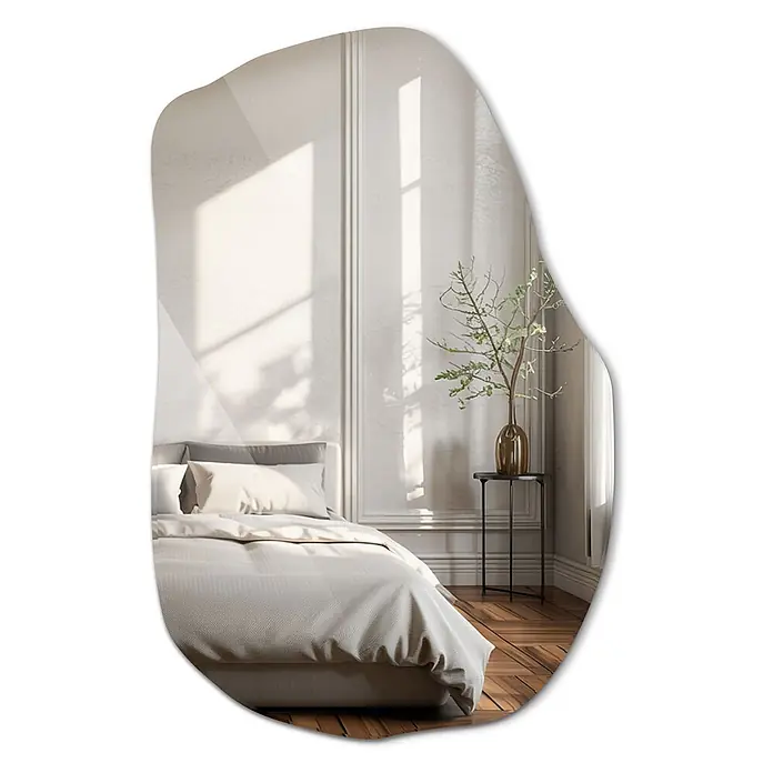 Tulup Wandspiegel - 65 x 100 cm - Unregelmäßig geformter Spiegel, der ein ruhiges Schlafzimmer mit gemütlichem Bett und Pflanze auf einem Beistelltisch reflektiert.