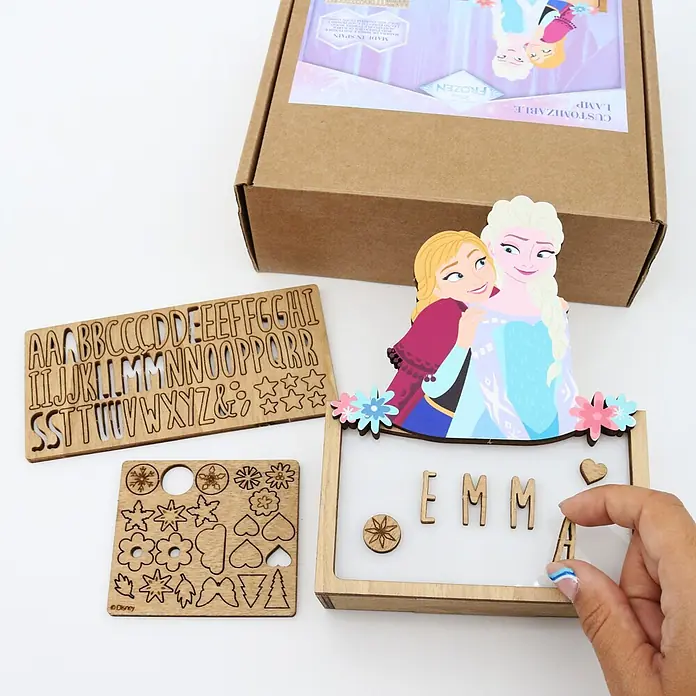 Lámpara de sobremesa infantil Elsa y Ana - 0,5 W, L x An x Al: 5 x 12,5 x 17 cm, Luz nocturna, Elsa y Ana - Kit de lámpara personalizable de Frozen con letras y formas de madera, siendo ensamblado. Muestra a Elsa y Anna.