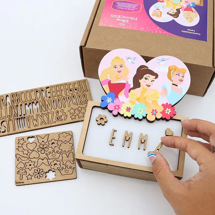 Lámpara de sobremesa infantil Princesas Disney - 0,5 W, L x An x Al: 5 x 12,5 x 17 cm, Luz nocturna, Princesas - Kit lámpara de madera personalizable Disney Princess con letras y formas de madera. Una mano coloca una letra para personalizarla.