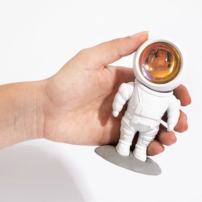 Mob Lámpara de sobremesa LED Astrolight Sun - 5 W, L x An x Al: 6,5 x 6 x 12 cm, Blanco, Blanco cálido, Sun - Proyector blanco con forma de astronauta con visera iridiscente y base gris, sostenido en una mano.