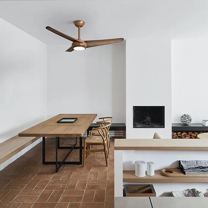 Sulion Ventilador de techo Chiwi - Marrón, 132 cm, 4 W - 34 W - Ventilador de techo marrón dorado con aspas de madera, iluminando un comedor moderno sobre una mesa de madera larga.