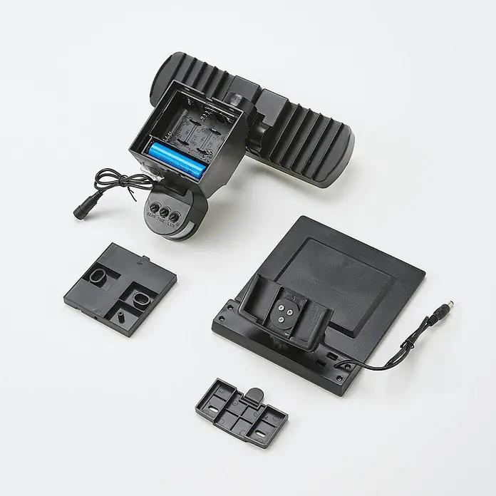 Arcchio Außenwandleuchte Lissano - schwarz, IP44 - Demontierte schwarze Solar-Bewegungsmelderleuchte, mit zwei LED-Köpfen, offenem Batteriefach, Sensor mit Reglern und Solarpanel.