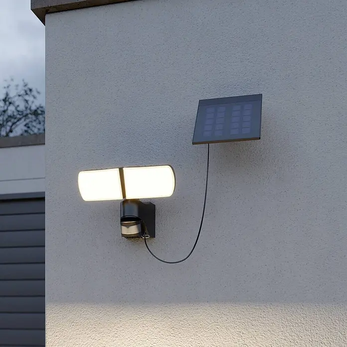 Arcchio Außenwandleuchte Lissano - schwarz, IP44 - Eine dunkelgraue Solar-Außenleuchte mit zwei hellweißen LED-Paneelen und Bewegungssensor, an einer Wand mit separatem Solarpanel montiert.