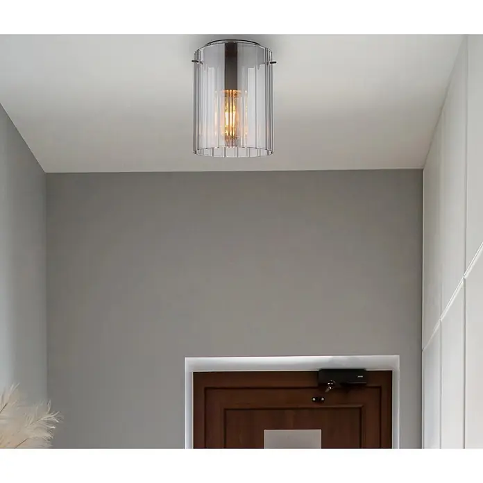 Globo Plafón - 40 W, Ø x Al: 180 x 230 mm, Gris oscuro, E27 - Un plafón moderno con pantalla de vidrio estriado transparente y bombilla de filamento cálido visible, iluminando un pasillo.