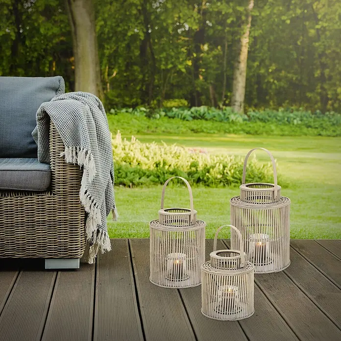 ECD Germany Windlicht Boho Bambus Laterne - Ø x H: 28,5 x 54,5 cm, Natur, 1 Stk. - Drei Bambuslaternen mit flackernden Kerzen auf einer Holzterrasse neben einem Gartenstuhl.