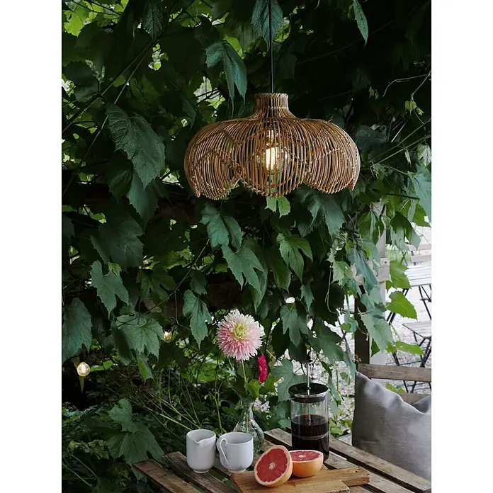 PR Home Außenwand- & Deckenleuchte 43cm Outdoor -  - Geflochtene Hängeleuchte aus Korbgeflecht mit leuchtender Glühbirne, zwischen grünem Laub über einem Gartentisch.