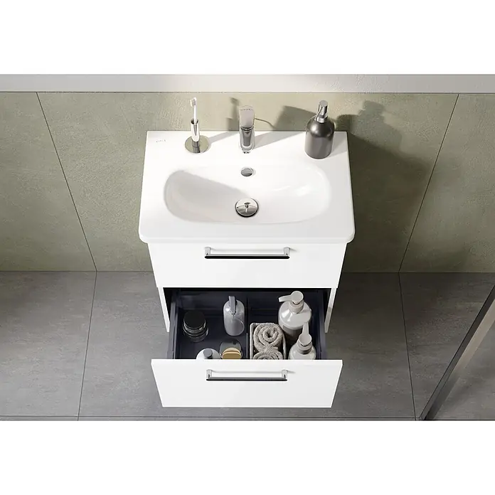 VitrA Root Flat Compact Badmöbel-Set Compact - B x T x H: 60 x 37 x 65 cm, Weiß, Hochglänzend - Weißer Badezimmerschrank mit integriertem Waschbecken, Chromarmaturen und geöffneter Schublade mit Pflegeprodukten und Handtüchern.
