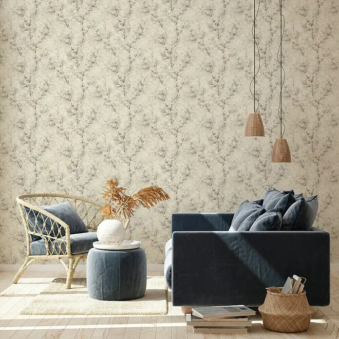 A.S. Création New Walls Vliestapete Bäume - Beige, Floral, 10,05 x 0,53 m - Elegantes Interieur mit einer stilvollen Couch, einem Rattansessel und einer dekorativen Wandtapete, die dem Raum eine gemütliche Atmosphäre verleiht.