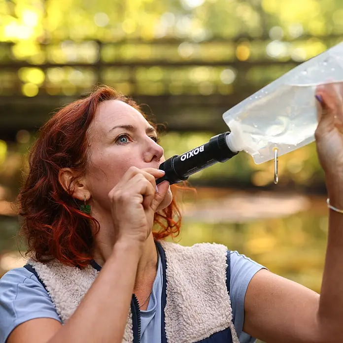 Boxio Wasserfilter - 3 -tlg. - Frau trinkt Wasser aus einer klaren Flasche mit schwarzem BOXIO Wasserfilter im Freien.