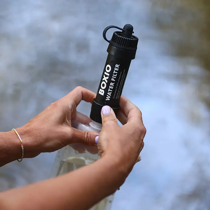 Boxio Eurobox Wash Up - L x B x H: 40 x 30 x 12 cm, Kunststoff - Eine Person hält einen schwarzen Wasserfilter und befestigt ihn an einer durchsichtigen Flasche, im Hintergrund verschwommenes Wasser.