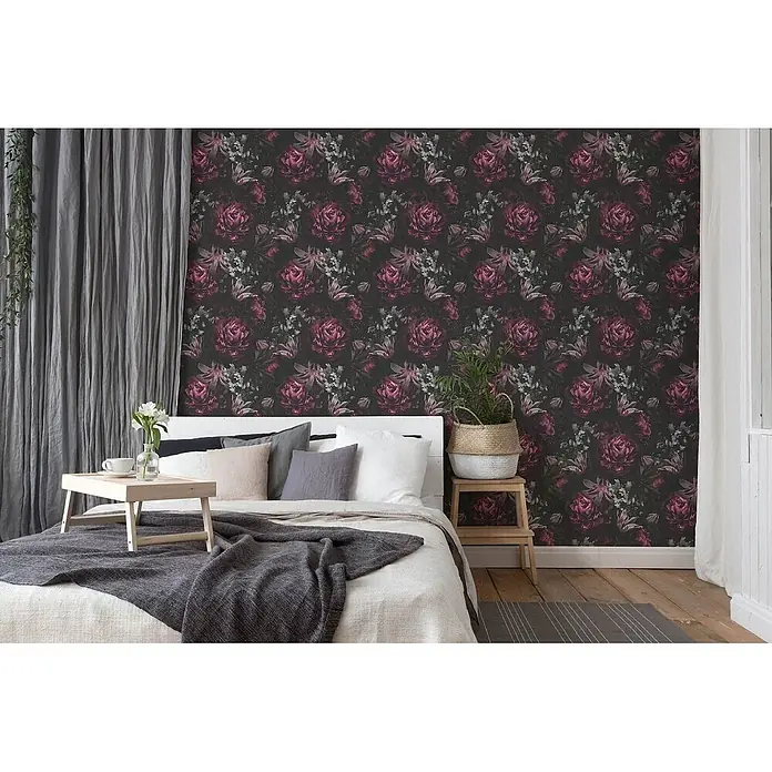 Profhome Vliestapete Heißgeprägte Vliestapete Floral in lila - graurosaschwarz, Floral, 10.050 x 530 mm - Dunkle Tapete mit einem Muster aus großen tiefrosa Rosen und hellgrünem Laub, die eine Wand hinter einem Bett in einem Schlafzimmer bedeckt.