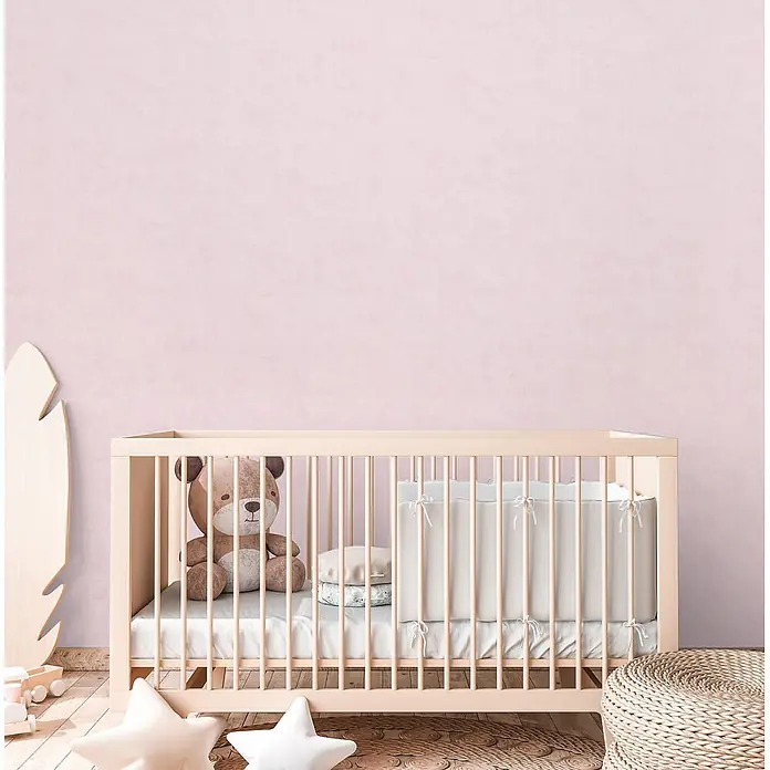 Profhome Vliestapete Vliestapete Kindertapete, Used Look, Textiloptik, Uni in rosa - rosa,lila, 10.050 x 530 mm - Helles Holzbettchen in gemütlichem Babyzimmer mit Teddybär, weißer Bettwäsche und Sternenkissen am Boden.