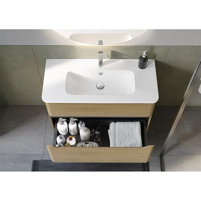 VitrA Integra Round Badmöbel-Set - Gesamtbreite Badmöbel: 100 cm, Eiche Gold - Moderne Waschtischkombination in Holzoptik mit weißem Waschbecken, Chromarmatur und geöffneter Schublade mit Pflegeprodukten und Handtüchern.