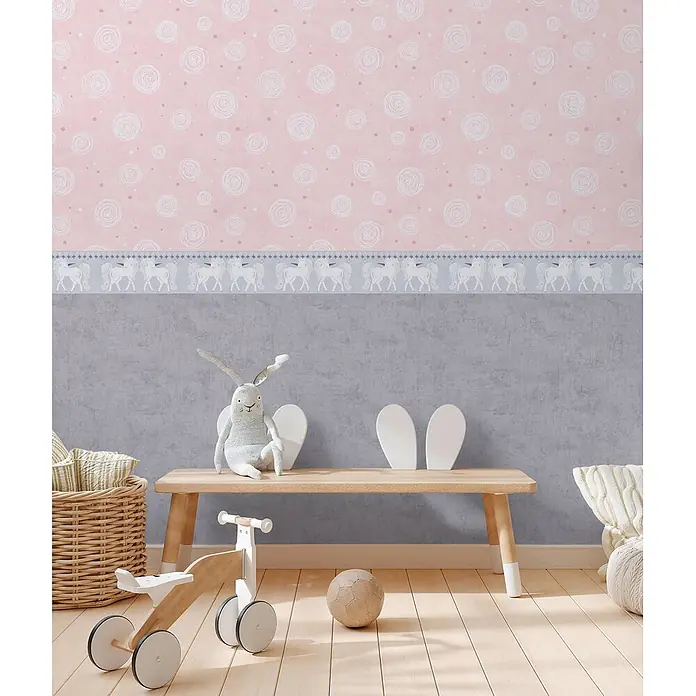 Profhome Vliestapete Vliestapete Grafisch, Kindertapete in rosa - alt-rosa, 10.050 x 530 mm - Kinderzimmer mit rosafarbener Tapete mit weißen Schnörkeln und einer grauen Einhorn-Bordüre, kombiniert mit einer grauen Wand. Holzsitzbank und Spielzeug.