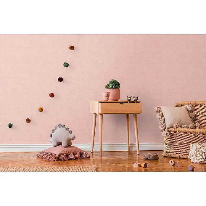 Profhome Vliestapete Vliestapete Kindertapete, Used Look, Textiloptik, Uni in rosa - lachs-rot, 10.050 x 530 mm - Kinderzimmer-Einrichtung mit Holznachttisch, Korbsessel, bunter Pompon-Girlande und Plüsch-Dinosaurier.