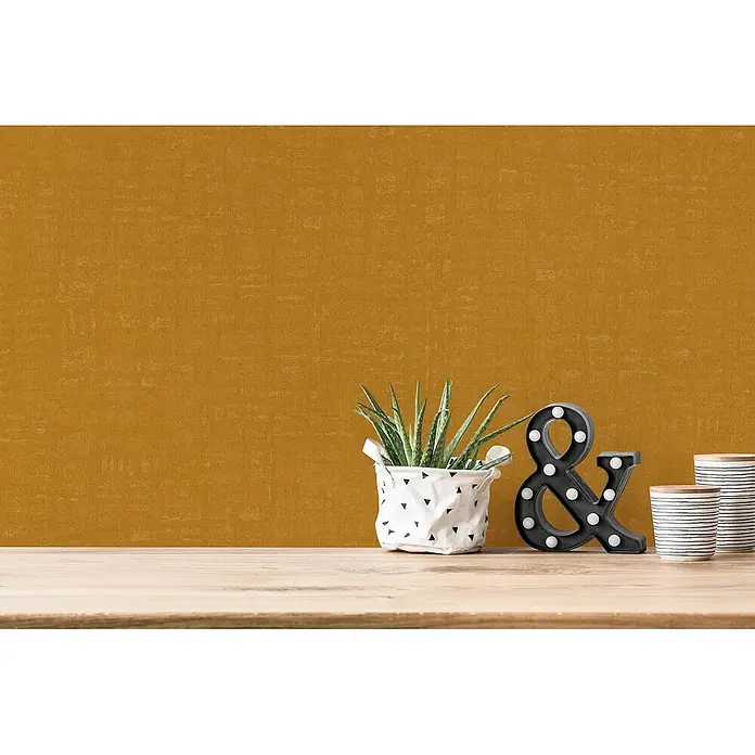Profhome Vliestapete Heißgeprägte Vliestapete Textiloptik in gelb - ocker-gelb, 10.050 x 530 mm - Strukturierte, senfgelbe Tapete als Raumhintergrund mit Holztisch und Dekoration.