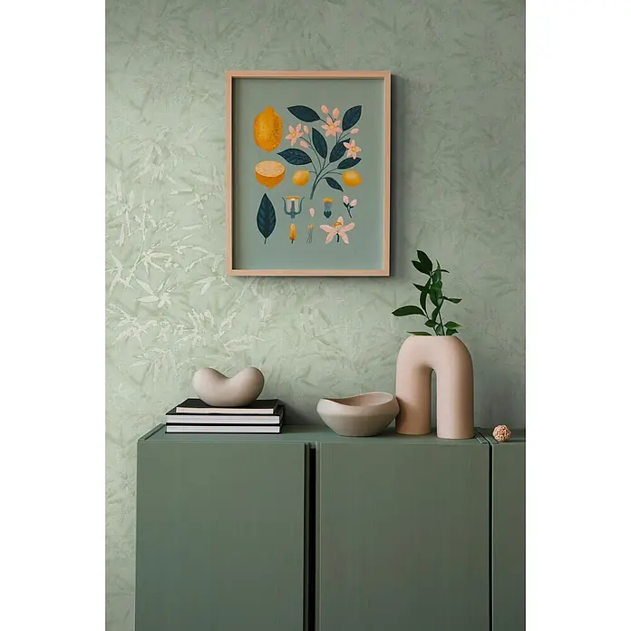 Profhome Vliestapete Heißgeprägte Vliestapete Ton-In-Ton, Floral, Textiloptik in grün - minz-grünsilber, 10.050 x 530 mm - Gerahmte botanische Kunst mit Zitronen und Blumen hängt über einem grünen Schrank mit minimalistischen Vasen und Objekten.