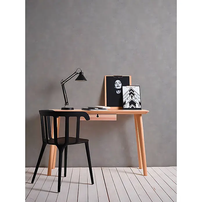 Profhome Vliestapete Vliestapete Uni grau - Uni, 10.050 x 530 mm - Ein heller Holzschreibtisch mit einer Schublade und einem schwarzen Stuhl, mit einer schwarzen Schreibtischlampe und zwei Bildern, als moderner Arbeitsplatz eingerichtet.