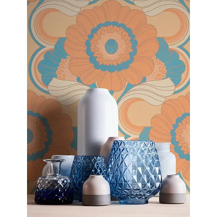 Profhome Vliestapete Heißgeprägte Vliestapete Blumen, Grafisch, Retro, Ornament beige - lachs-orangepastell-gelb, 8.500 x 530 mm - Eine Sammlung weißer, blauer und zweifarbiger Deko-Vasen und -Objekte vor einer lebhaften Retro-Blumentapete.