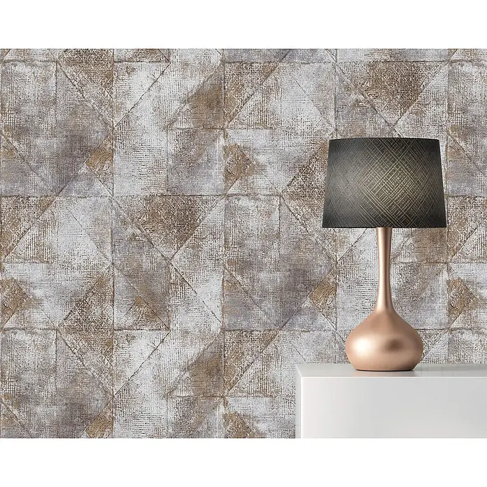 Profhome Vliestapete Vliestapete Geometrisch, Used Look, Spachteloptik, Rauten Muster in gold - grau, 10.050 x 530 mm - Elegante Tischleuchte mit dunklem, strukturiertem Schirm und schlankem roséfarbenem Sockel auf einer weißen Oberfläche.
