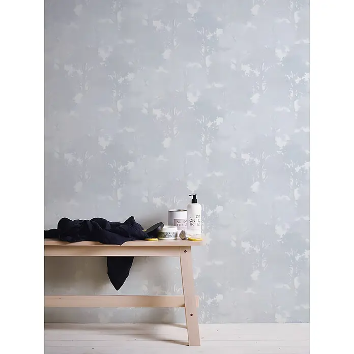Profhome Vliestapete Vliestapete Wald grau - 10.050 x 530 mm - Holzbank mit Badprodukten und einem schwarzen Handtuch in einem hellen Raum.
