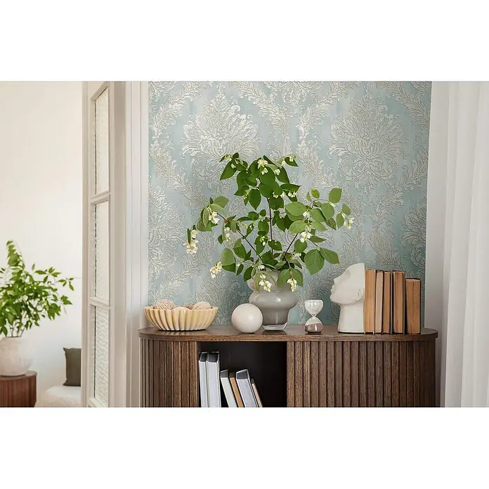 Profhome Vliestapete Heißgeprägte Vliestapete Textiloptik, Ornament, Barock in blau - pastell-türkis, 10.050 x 530 mm - Hellblaue Tapete mit elegantem silbernem Damastmuster schmückt eine Wand in einem stilvollen Raum.
