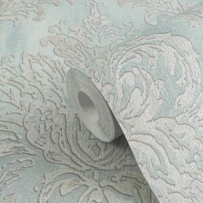 Profhome Vliestapete Heißgeprägte Vliestapete Textiloptik, Ornament, Barock in blau - pastell-türkis, 10.050 x 530 mm - Hellblaue Tapetenrolle mit erhabenem, metallischem Silber-Damaschkmuster. Die texturierte Oberfläche ist teilweise abgerollt.