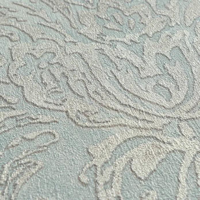 Profhome Vliestapete Heißgeprägte Vliestapete Textiloptik, Ornament, Barock in blau - pastell-türkis, 10.050 x 530 mm - Nahaufnahme von hellblauer gemusterter Textiltapete mit erhabenem, strukturiertem Ornamentdesign in Hellbeige.
