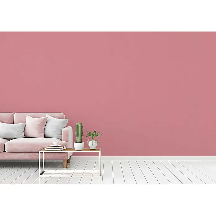 Profhome Vliestapete Vliestapete Uni in rosa - Uni, 10.050 x 530 mm - Rosa Wand in einem modernen Wohnraum mit pastellfarbenem Sofa und Pflanzen auf weißem Holzboden.