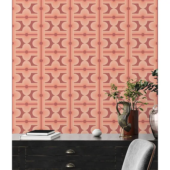 Profhome Vliestapete Heißgeprägte Vliestapete Grafisch, Retro, Geometrisch, Ornament in rot - braunlachs-rotpastell-orange, 8.500 x 530 mm - Retro geometrische Tapete in Pfirsich- und Terrakottatönen an einer Wand hinter einem dunklen Holzschreibtisch mit Pflanzen.