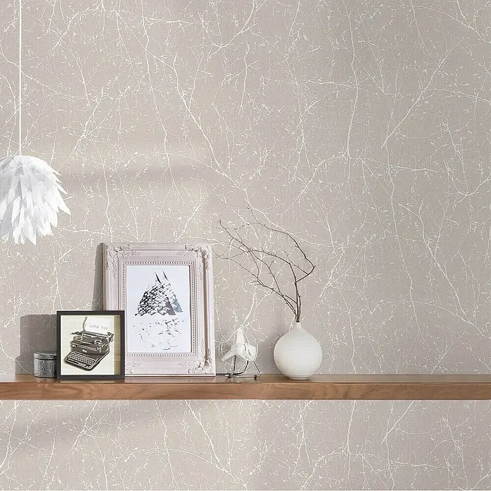 Profhome Vliestapete Vliestapete Floral in creme - perl-weiß, Floral, 10.050 x 530 mm - Hellbeige Tapete mit zartem weißem Astmuster an einer Wand über einem Holzregal mit Deko.