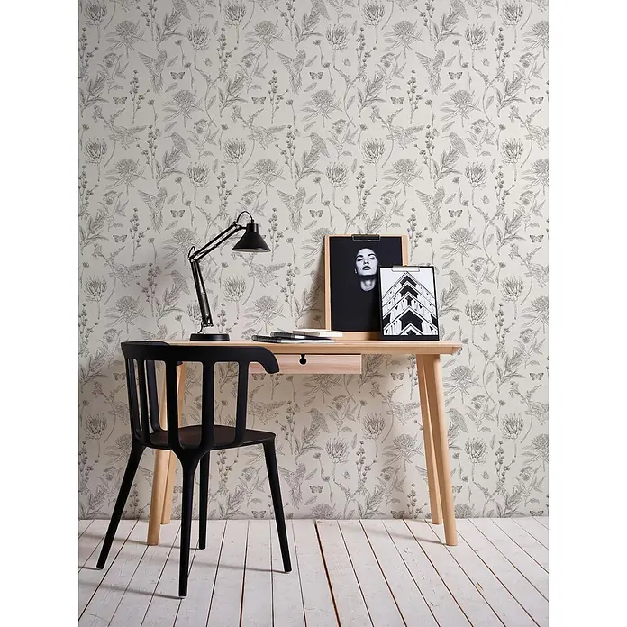 Profhome Vliestapete Vliestapete Blumen, Landhaus, Floral, Toile De Jouy, Vogelmuster, weiß - schwarz, 10.050 x 530 mm - Schreibtisch aus hellem Holz mit schwarzem Stuhl und Lampe in einem Raum mit gemusterter Tapete. Notizbuch und gerahmte Kunst auf dem Tisch.