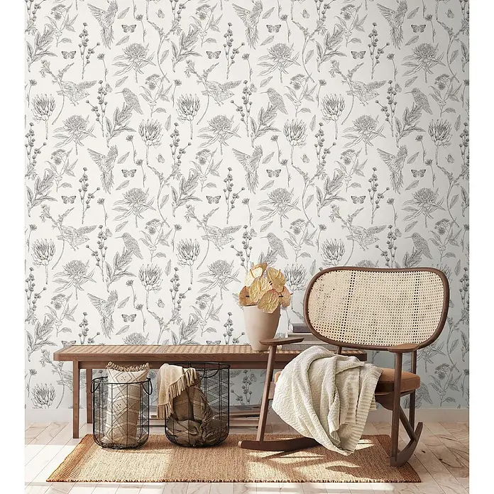 Profhome Vliestapete Vliestapete Blumen, Landhaus, Floral, Toile De Jouy, Vogelmuster, weiß - schwarz, 10.050 x 530 mm - Tapete mit botanischem und Vogelmuster im Schwarz-Weiß-Stil, an einer Wand hinter einer Bank und einem Stuhl.